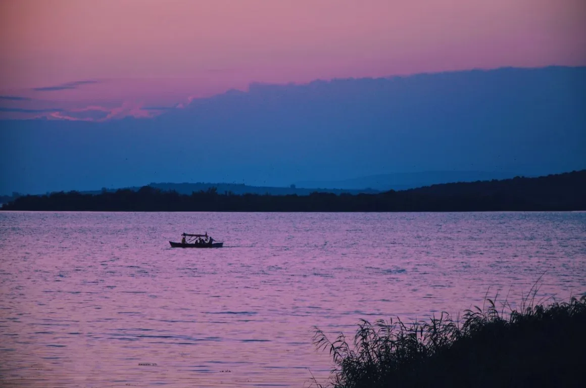 A distant boat on a purple lake at dusk