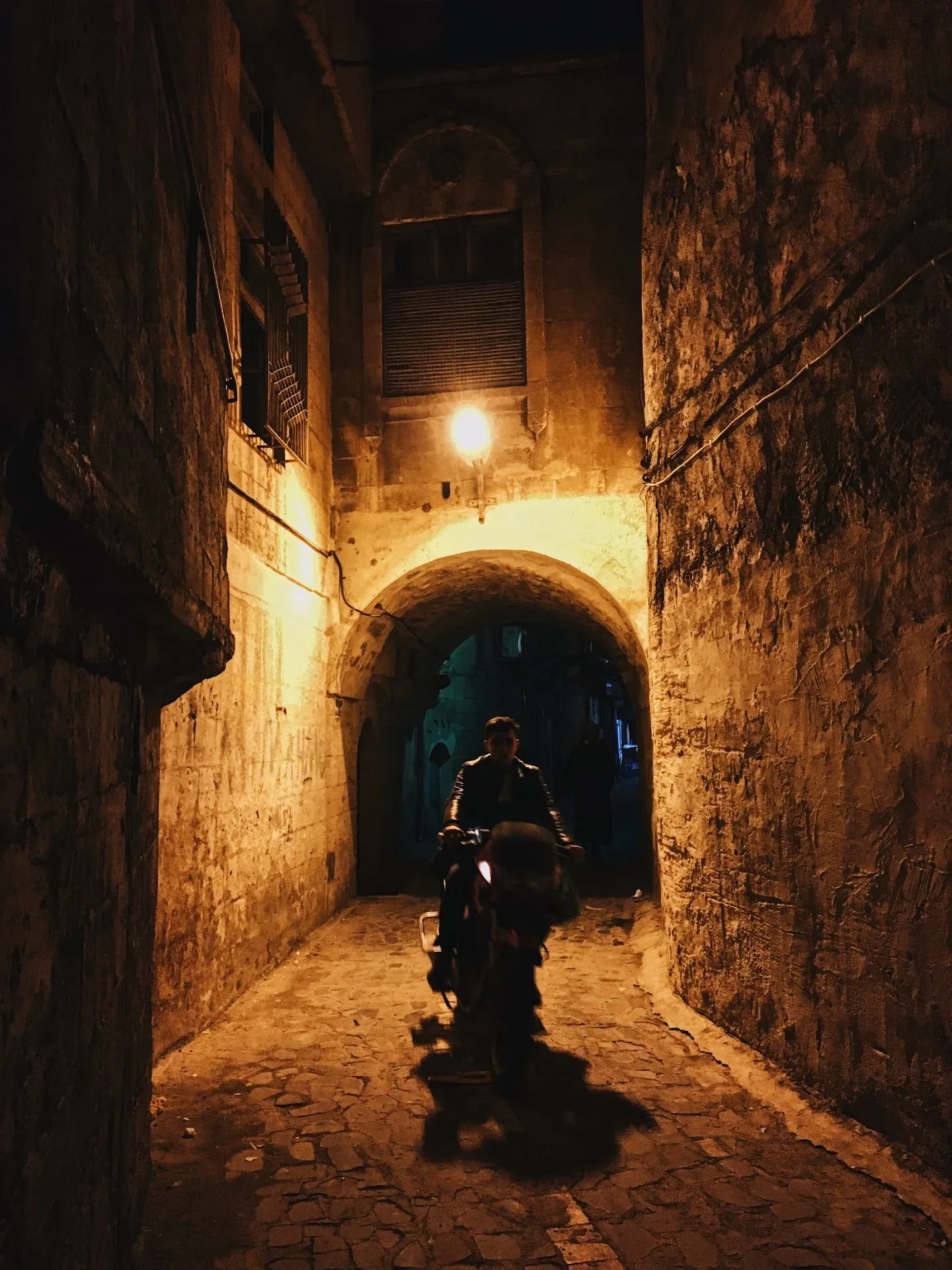 A motorcyclist passing through a stone arch