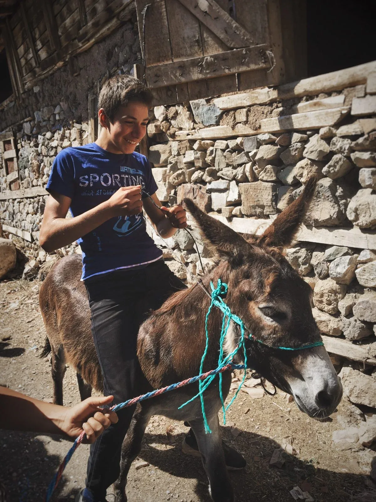 A boy riding a donkey in a stone village